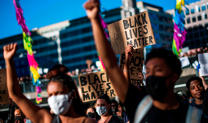 Demonstranter med hævede næver og skilte med teksten "Black Lives Matter"